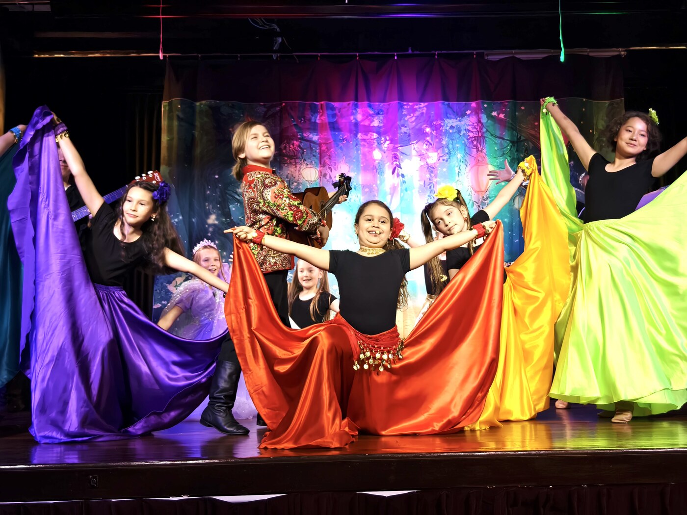 Students dancing on stage in colourful flowing costumes