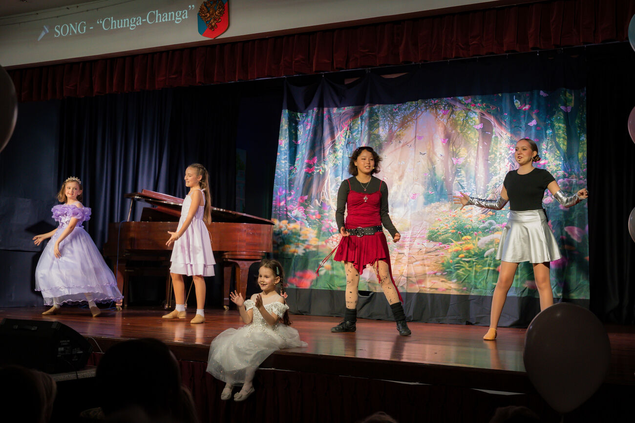 Group of students dancing together on stage in front of a fairy-tale backdrop