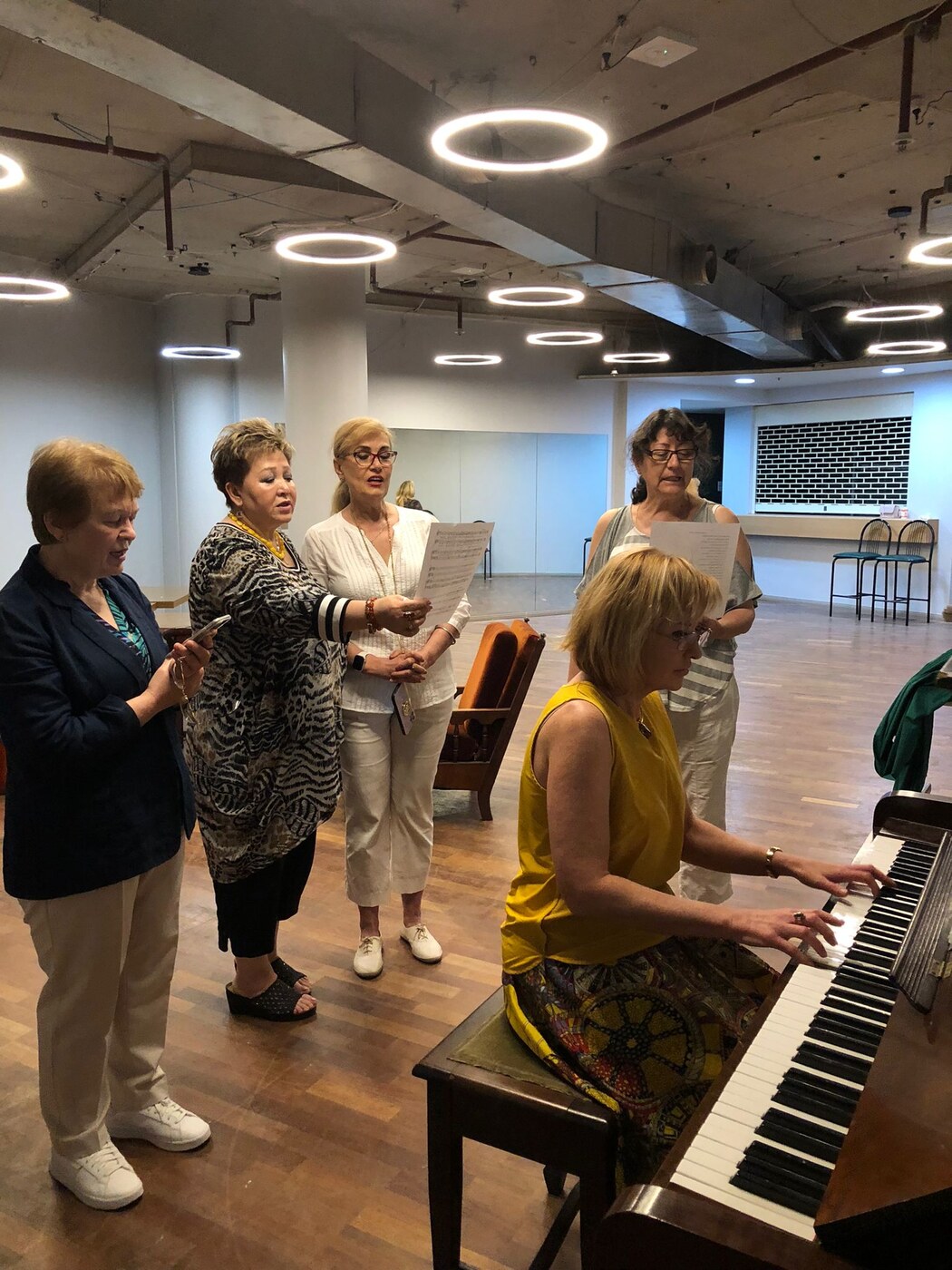 A group of adults singing together at the piano