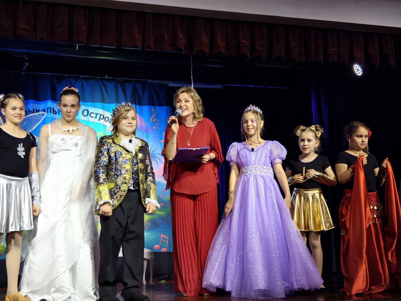 Full cast on stage with the director addressing the audience