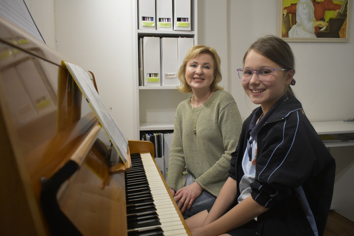 Natalie Mitz guiding a student through a piece at the piano