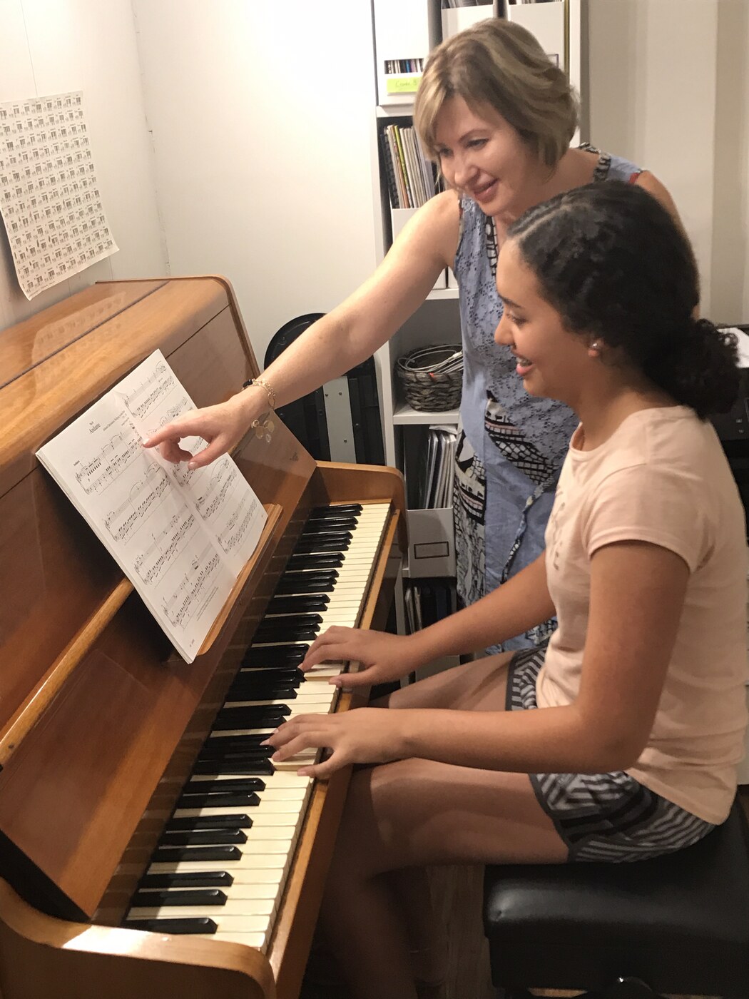 Natalie Mitz teaching a student at the piano, pointing to sheet music